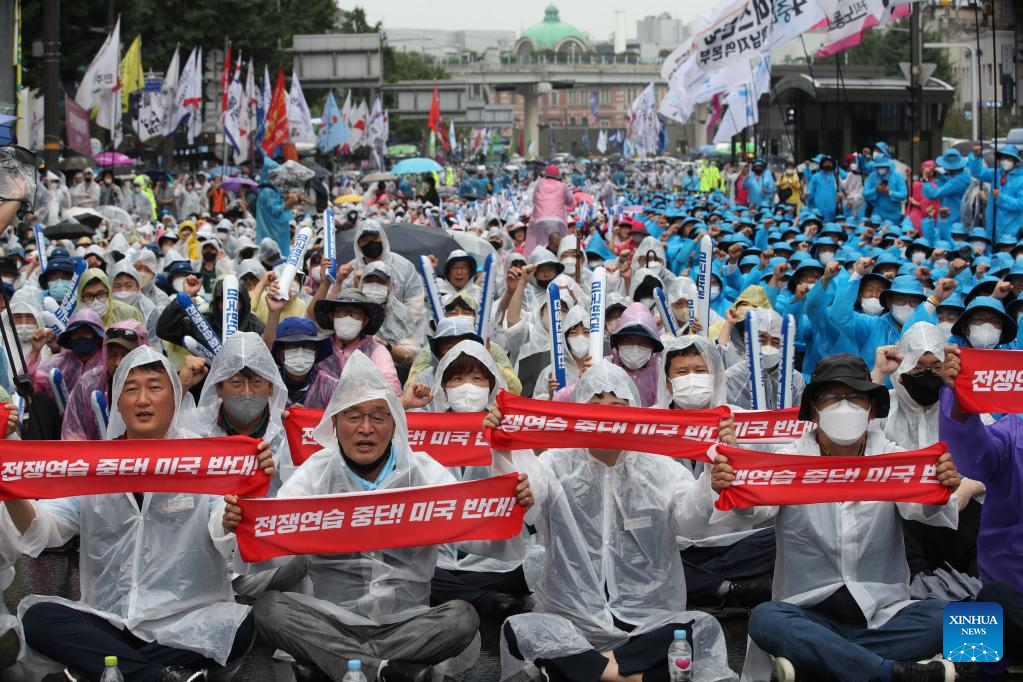 Koreans protesting holding red signs against war exercises